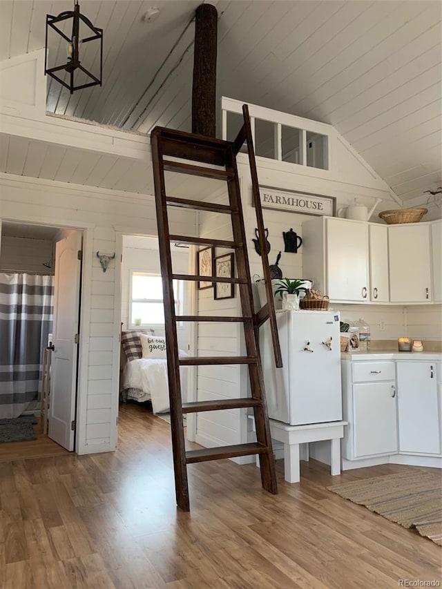 kitchen with vaulted ceiling, decorative light fixtures, white cabinetry, wooden ceiling, and hardwood / wood-style floors