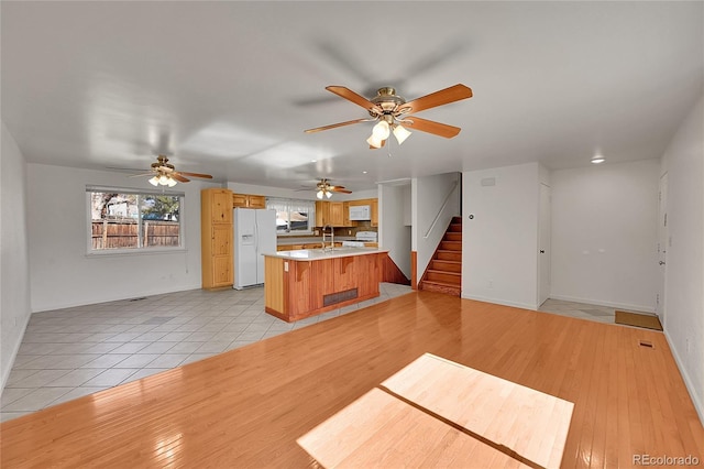 kitchen featuring light countertops, a sink, light wood-type flooring, white appliances, and a peninsula