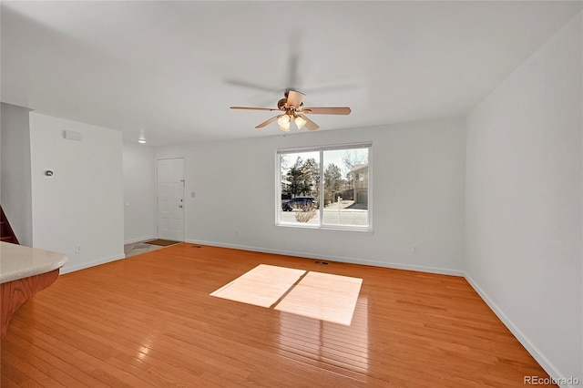 spare room with a ceiling fan, baseboards, and light wood finished floors