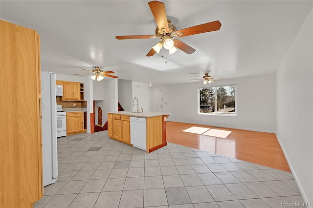 kitchen featuring light tile patterned flooring, white appliances, a sink, open floor plan, and light countertops