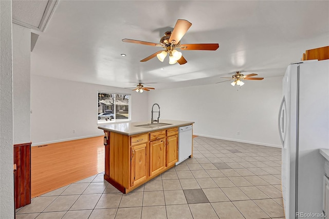 kitchen featuring white appliances, light tile patterned floors, open floor plan, light countertops, and a sink