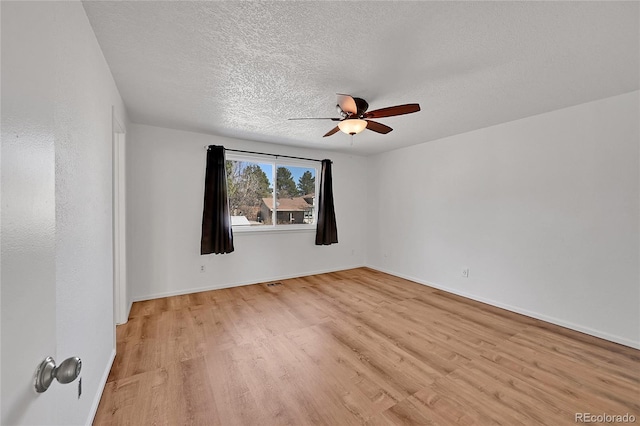 spare room featuring ceiling fan, a textured ceiling, baseboards, and light wood-style floors