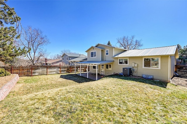 rear view of property featuring metal roof, a patio, a fenced backyard, central air condition unit, and a yard