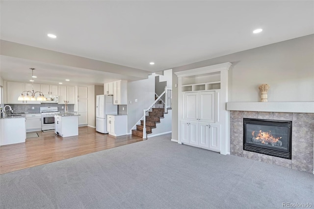 unfurnished living room featuring hardwood / wood-style flooring, a tiled fireplace, and sink