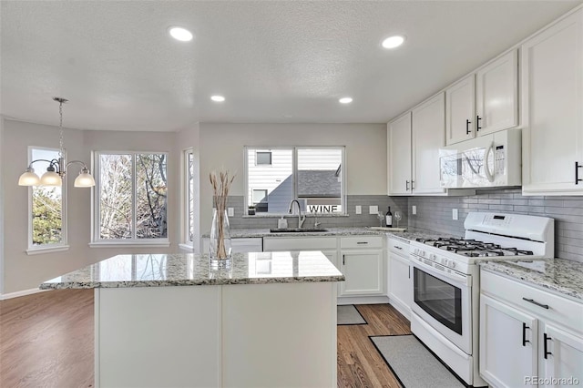 kitchen featuring white appliances, dark wood-type flooring, white cabinets, sink, and a chandelier