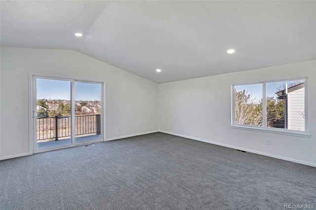 unfurnished room with plenty of natural light, vaulted ceiling, and dark colored carpet