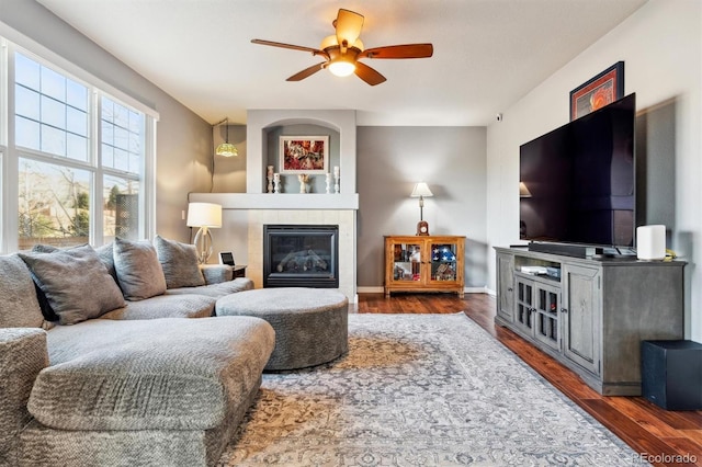 living room featuring ceiling fan, dark wood-type flooring, and a fireplace