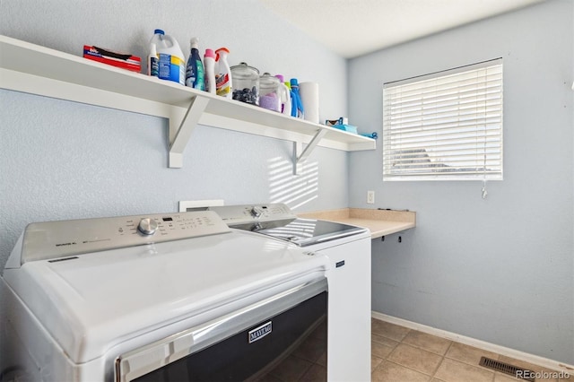 laundry room featuring washing machine and dryer and light tile patterned floors