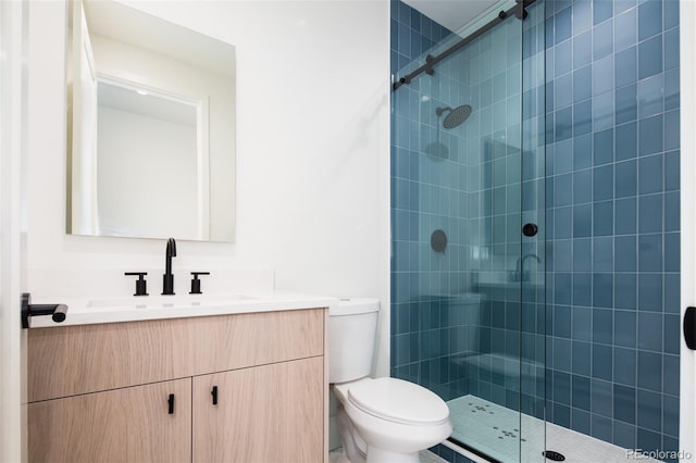 bathroom featuring a shower with shower door, toilet, and vanity