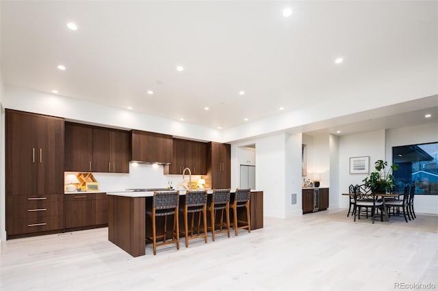 kitchen featuring a kitchen bar, dark brown cabinets, and a kitchen island with sink