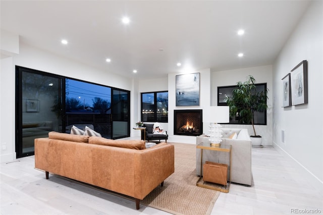 living area with a warm lit fireplace, baseboards, light wood-style flooring, and recessed lighting