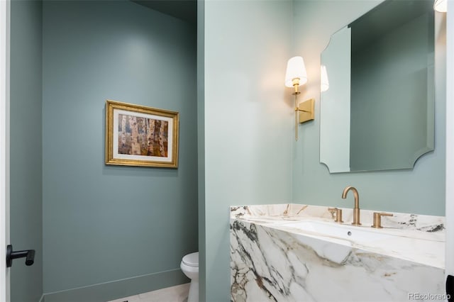 half bath featuring toilet, baseboards, and vanity