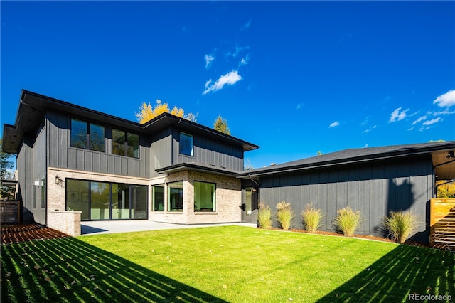 back of property with brick siding, a lawn, and a patio