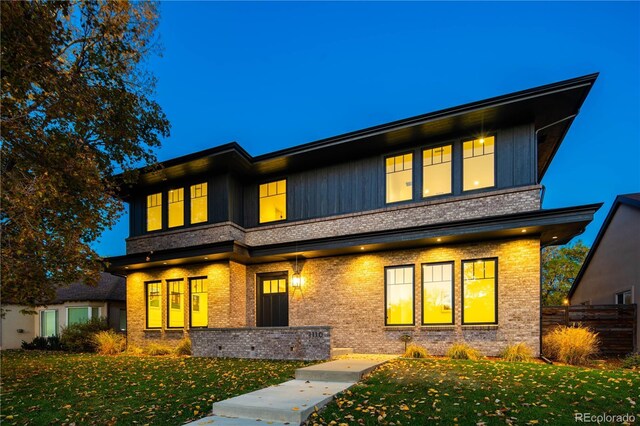 view of front of property featuring brick siding, fence, and a front yard