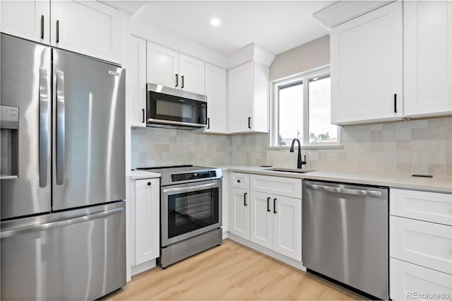 kitchen featuring white cabinets, stainless steel appliances, sink, and light hardwood / wood-style flooring