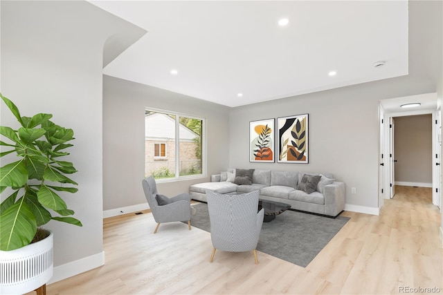 living room featuring light wood-type flooring, baseboards, and recessed lighting