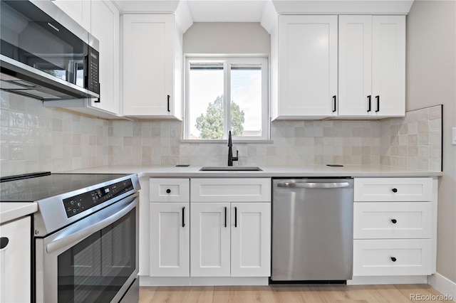 kitchen featuring appliances with stainless steel finishes, light countertops, a sink, and white cabinetry