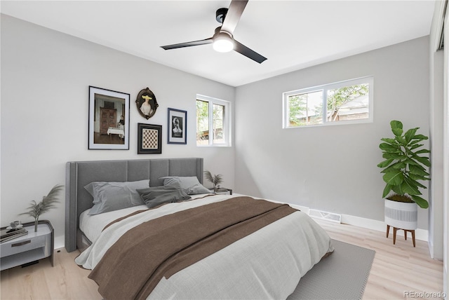 bedroom featuring light wood finished floors, baseboards, visible vents, and ceiling fan