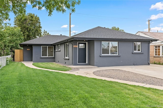 view of front of home with a front yard, roof with shingles, fence, and stucco siding