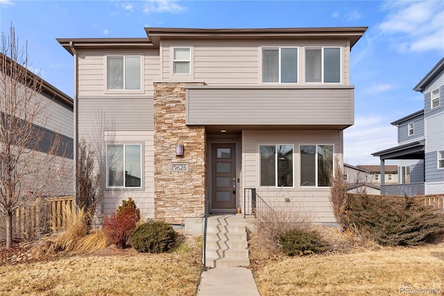 view of front facade with stone siding and fence