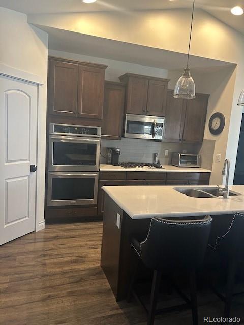 kitchen featuring sink, decorative light fixtures, appliances with stainless steel finishes, dark hardwood / wood-style floors, and backsplash