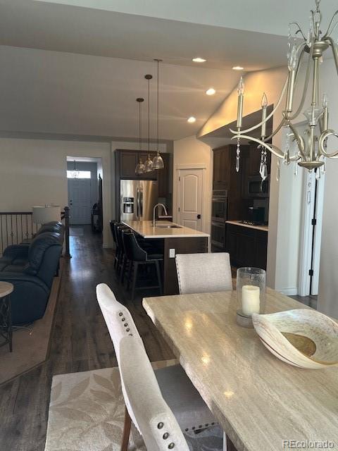 dining area with dark wood-type flooring, a chandelier, and sink