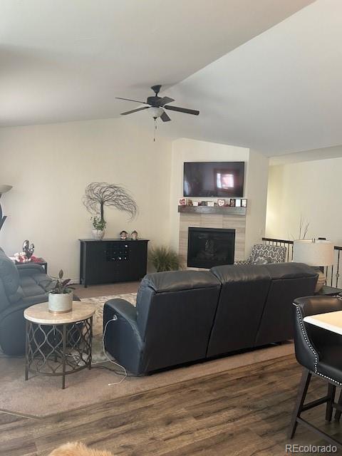 living room with ceiling fan, lofted ceiling, dark hardwood / wood-style flooring, and a tile fireplace