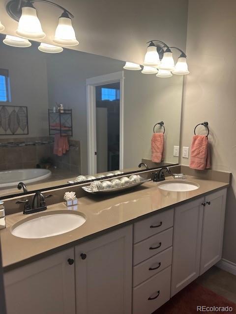 bathroom with double vanity, an inviting chandelier, and a sink