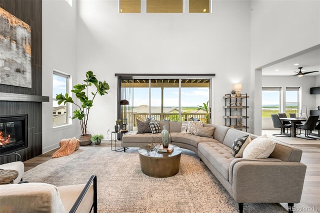 16262 W 95th Ln, Arvada, CO 80007 - living room featuring a towering ceiling, wood finished floors, a fireplace, a ceiling fan, and recessed lighting