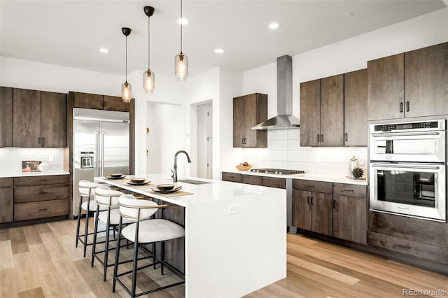 16262 W 95th Ln, Arvada, CO 80007 - kitchen with wall chimney exhaust hood, stainless steel appliances, a breakfast bar, tasteful backsplash, and dark brown cabinetry