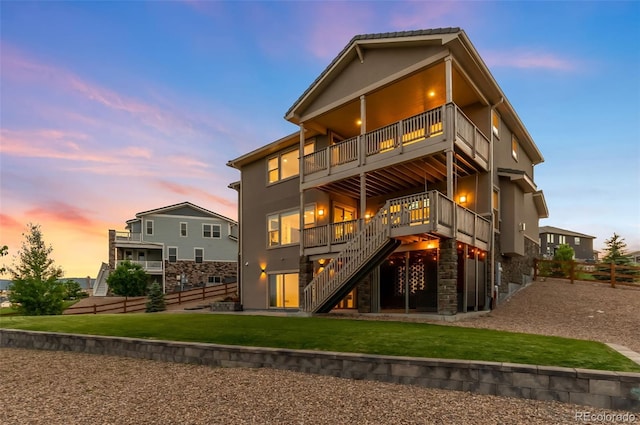16262 W 95th Ln, Arvada, CO 80007 - back of house at dusk featuring a balcony, stairway, stucco siding, and stone siding