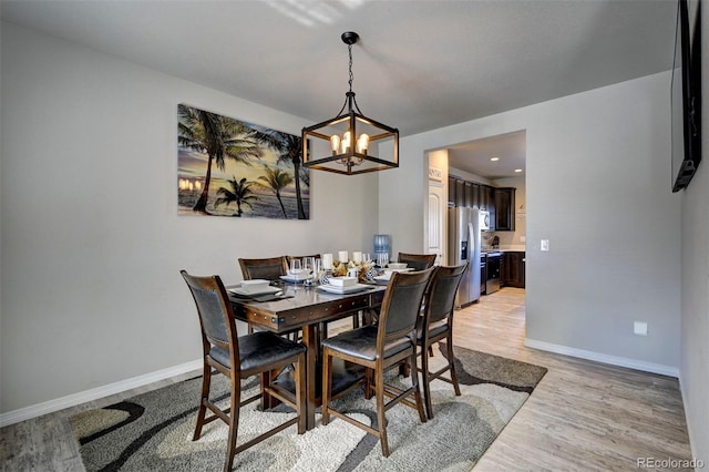 dining room with light hardwood / wood-style floors and a chandelier