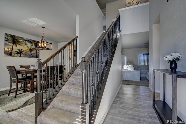 stairs with hardwood / wood-style flooring, a chandelier, and a towering ceiling