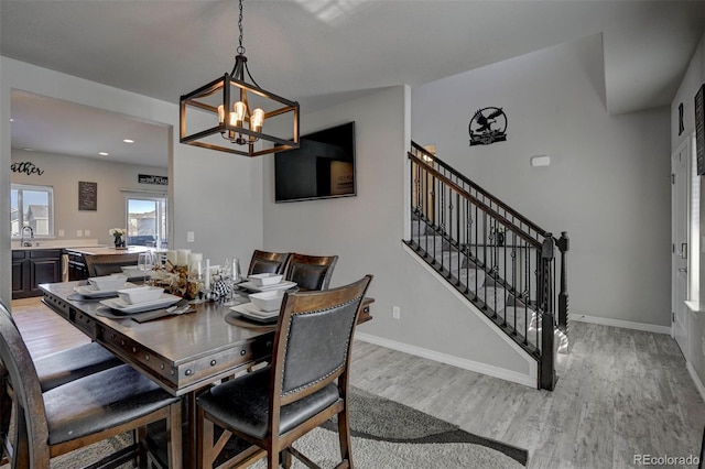 dining space featuring sink, an inviting chandelier, and light hardwood / wood-style flooring