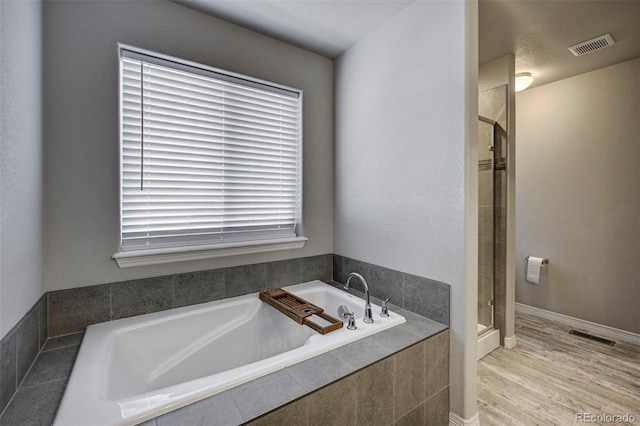 bathroom featuring wood-type flooring and plus walk in shower