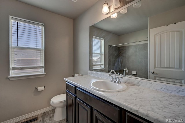 bathroom featuring hardwood / wood-style flooring, vanity, toilet, and a tile shower