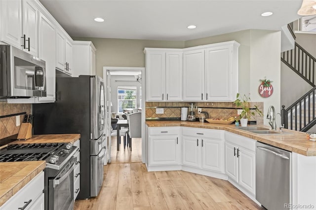 15021 Josephine St, Thornton, CO 80602 - kitchen with appliances with stainless steel finishes, white cabinetry, light wood finished floors, decorative backsplash, and recessed lighting