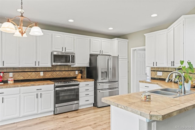 15021 Josephine St, Thornton, CO 80602 - kitchen with stainless steel appliances, white cabinetry, tasteful backsplash, light wood-type flooring, and a peninsula