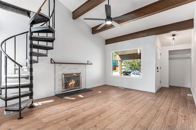 unfurnished living room featuring a ceiling fan, a fireplace, lofted ceiling with beams, stairway, and baseboards