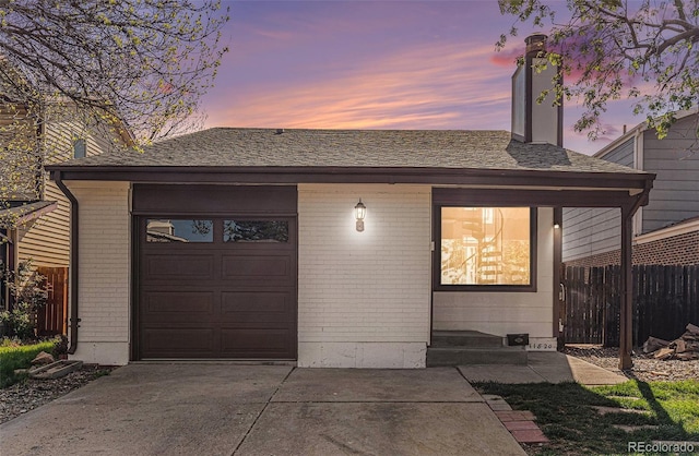 view of front of home featuring concrete driveway, brick siding, fence, and an attached garage