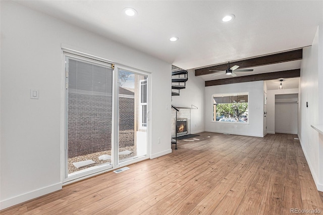 unfurnished living room featuring light wood finished floors, baseboards, and a ceiling fan