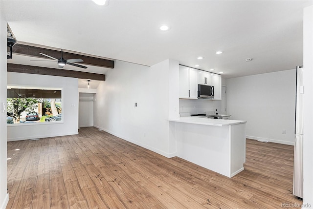 kitchen with stainless steel microwave, light wood-type flooring, a ceiling fan, and white cabinets