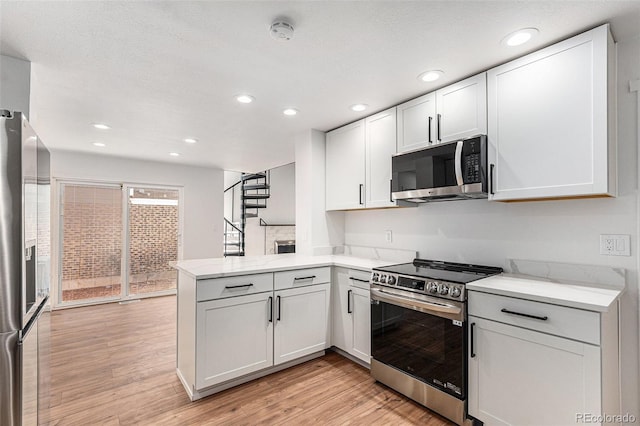 kitchen with a peninsula, recessed lighting, light wood finished floors, white cabinetry, and appliances with stainless steel finishes
