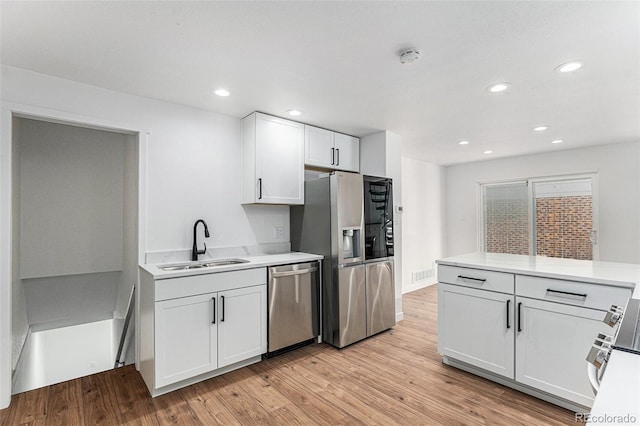 kitchen featuring light countertops, stainless steel appliances, light wood-type flooring, and a sink