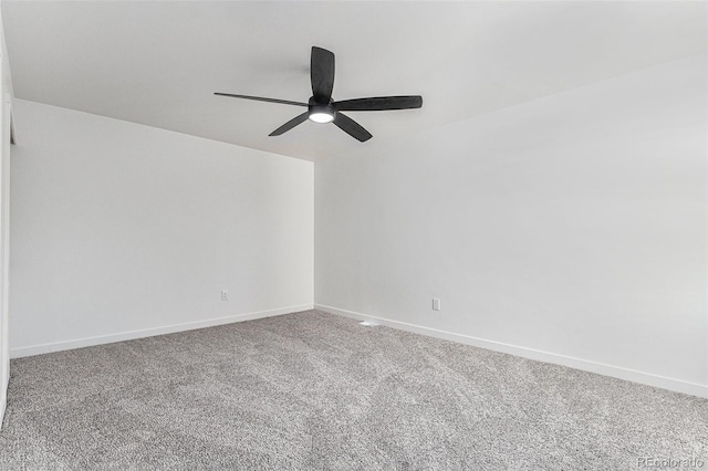 carpeted spare room featuring baseboards and a ceiling fan