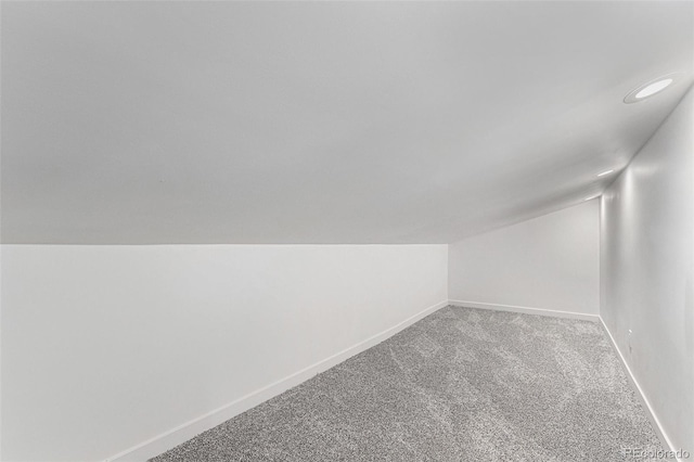 additional living space with vaulted ceiling, light colored carpet, baseboards, and recessed lighting