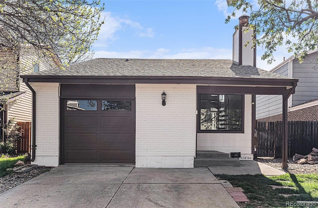 garage featuring fence and concrete driveway