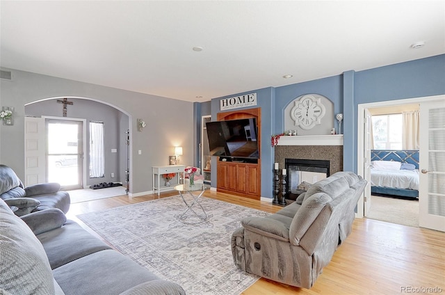 9994 Quintero St, Commerce City, CO 80022 - living room with arched walkways, light wood finished floors, and a glass covered fireplace