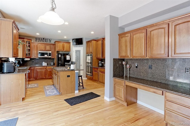 9994 Quintero St, Commerce City, CO 80022 - kitchen featuring stainless steel appliances, a kitchen breakfast bar, a sink, a center island, and light wood-style flooring