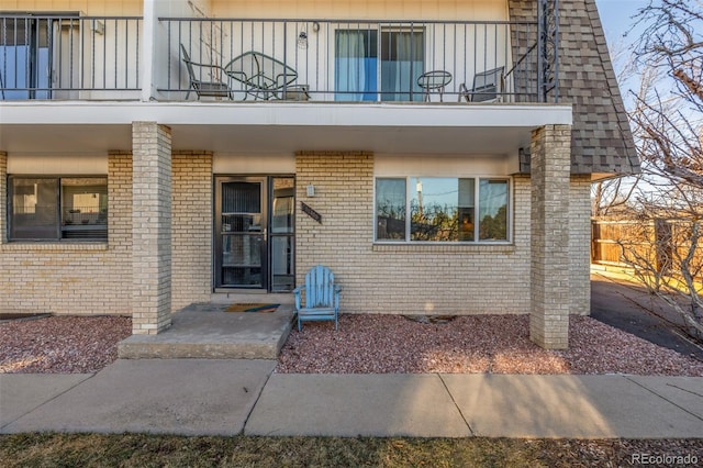 entrance to property with a balcony, board and batten siding, and brick siding